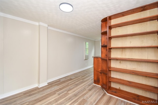 basement with crown molding and light hardwood / wood-style flooring