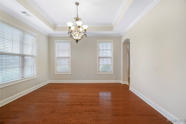 empty room featuring dark hardwood / wood-style floors, ornamental molding, a raised ceiling, and a chandelier