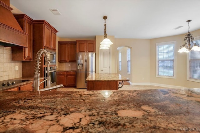 kitchen with appliances with stainless steel finishes, arched walkways, a chandelier, and backsplash