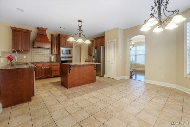 kitchen featuring decorative light fixtures, premium range hood, a center island, sink, and stainless steel appliances