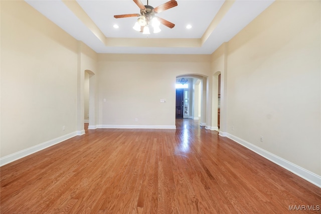 spare room with ceiling fan, a raised ceiling, and light hardwood / wood-style floors