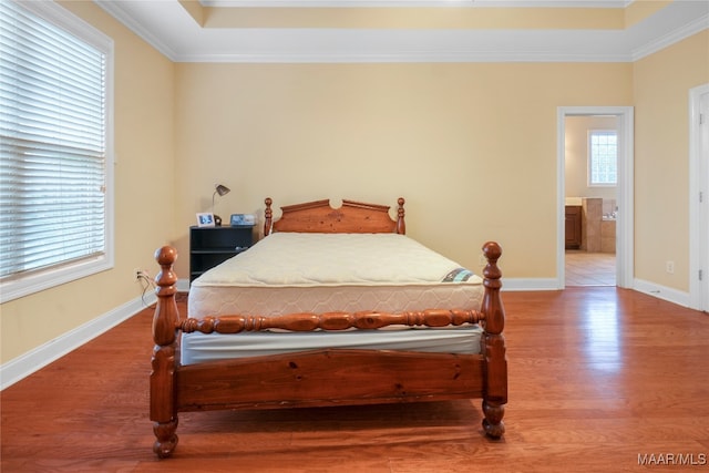 bedroom featuring ornamental molding, connected bathroom, and hardwood / wood-style flooring