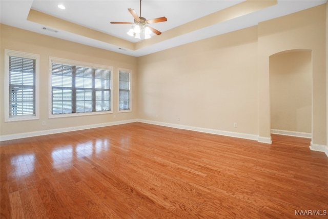 spare room with ceiling fan, light hardwood / wood-style flooring, and a raised ceiling