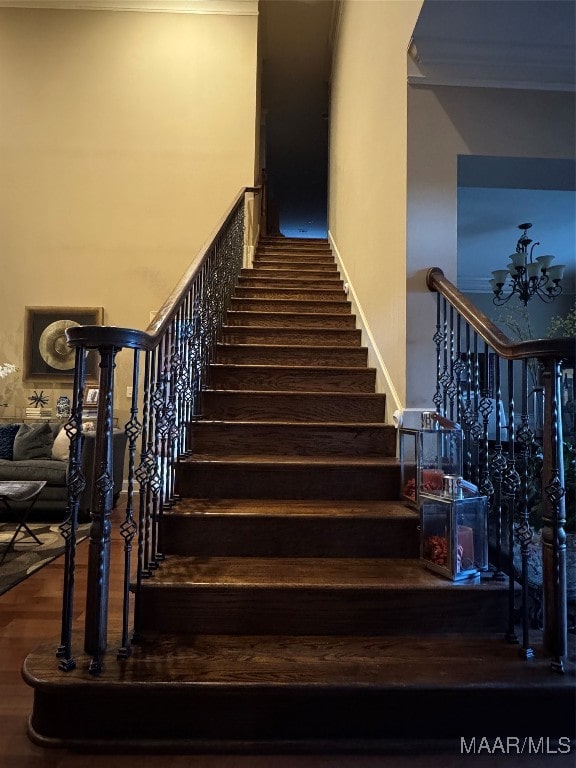 stairway featuring hardwood / wood-style flooring, ornamental molding, and an inviting chandelier