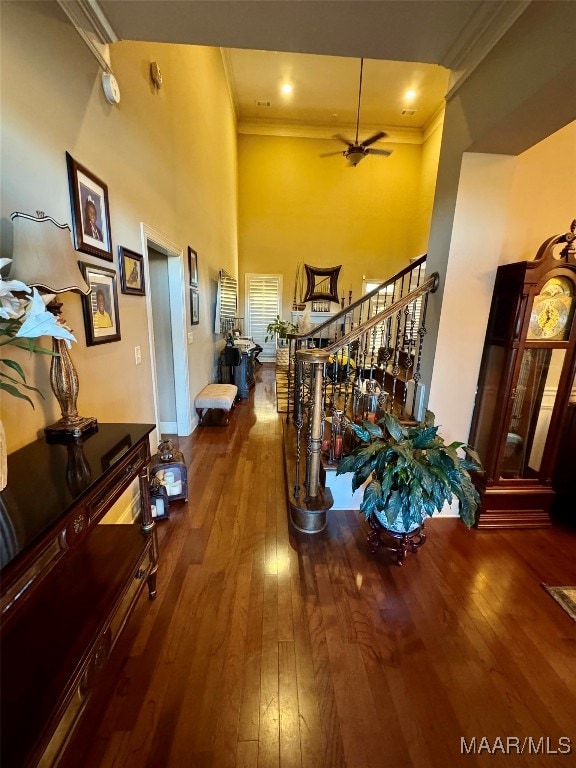 corridor featuring ornamental molding, hardwood / wood-style floors, and a towering ceiling