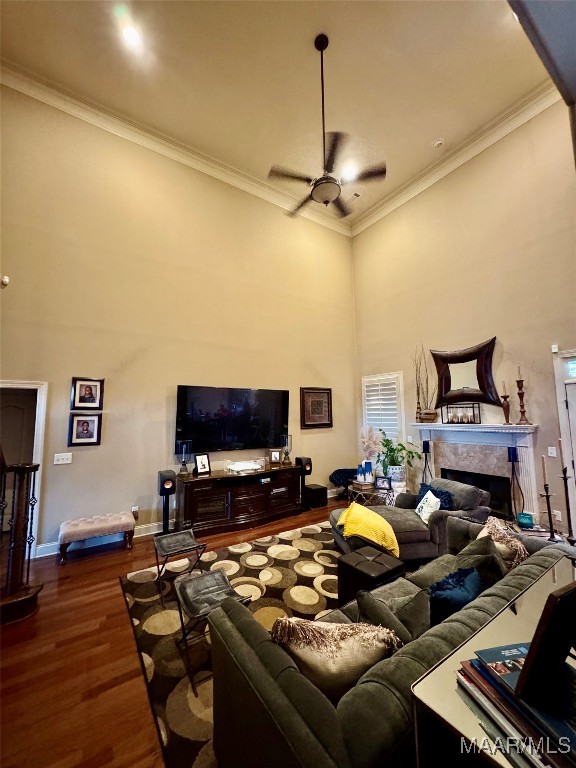 living room with ornamental molding, dark wood-type flooring, a towering ceiling, and ceiling fan