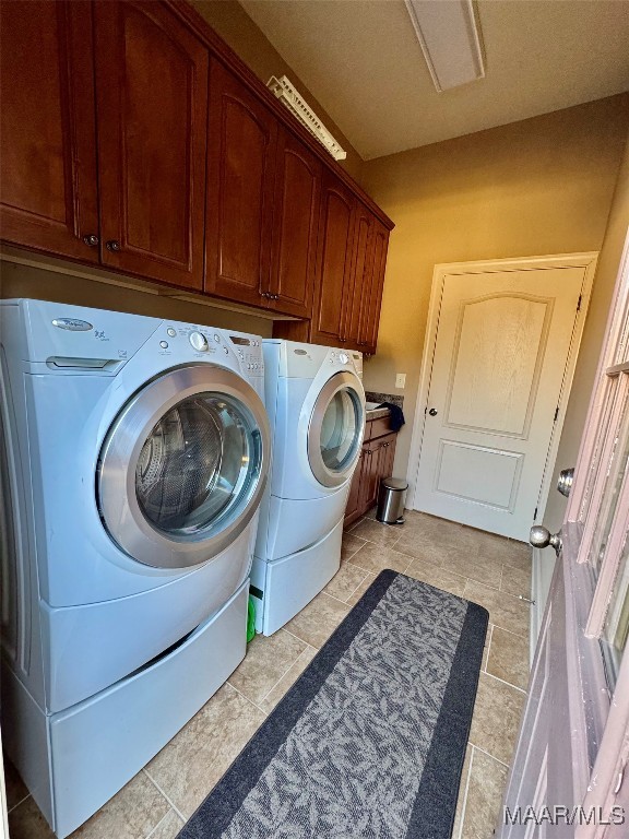 laundry room with light tile patterned floors, cabinets, and separate washer and dryer