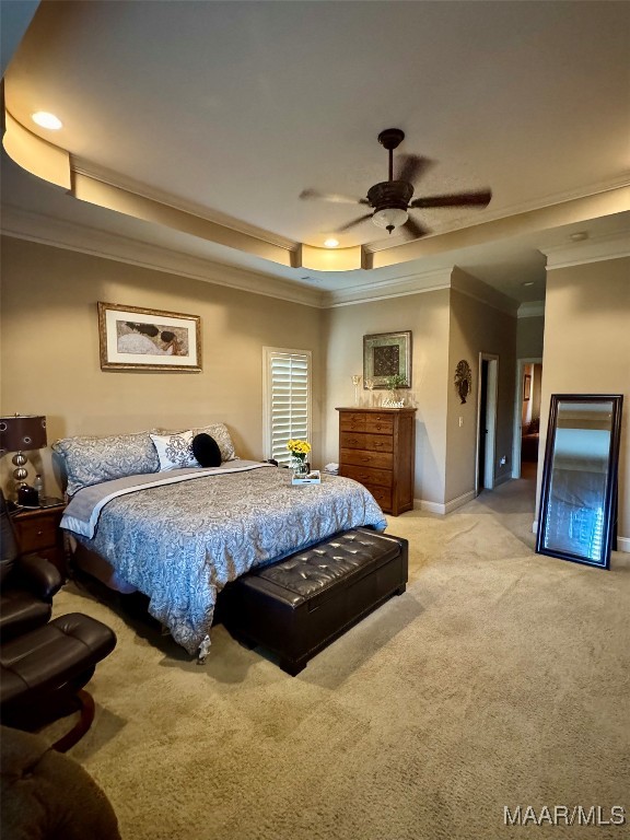 carpeted bedroom featuring crown molding, a tray ceiling, and ceiling fan