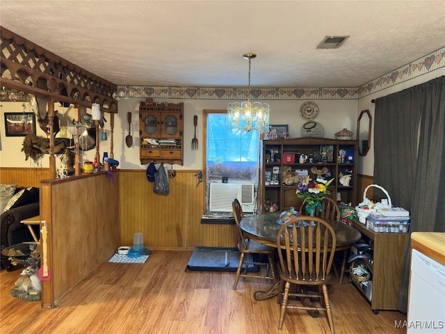 dining area with wood walls, a textured ceiling, and light wood-type flooring