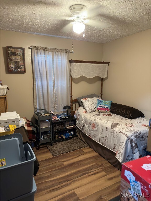 bedroom featuring hardwood / wood-style flooring, ceiling fan, and a textured ceiling