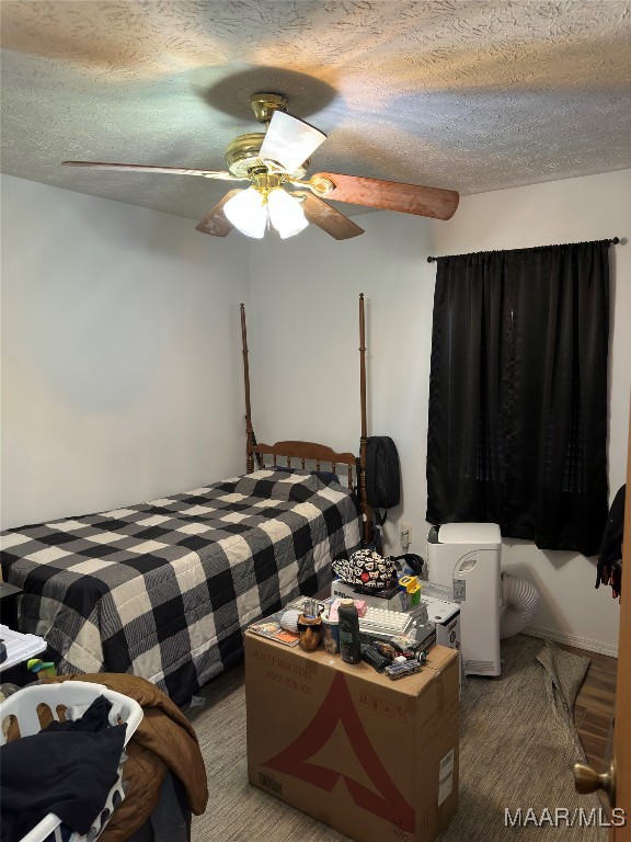 bedroom featuring hardwood / wood-style floors, a textured ceiling, and ceiling fan