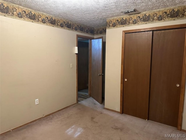 unfurnished bedroom with baseboards, a closet, a textured ceiling, and visible vents