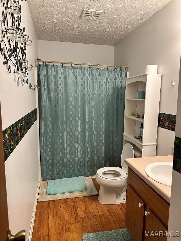 full bathroom with wood finished floors, curtained shower, a textured ceiling, and visible vents