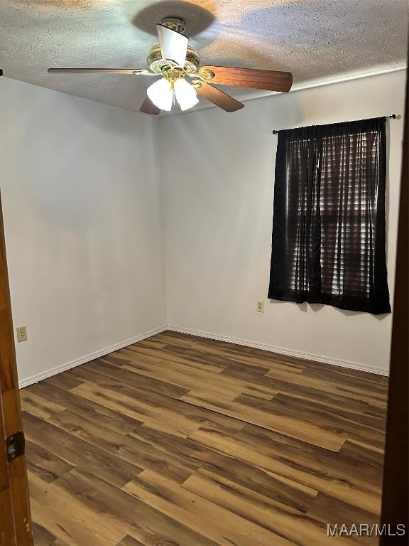 empty room with baseboards, a ceiling fan, a textured ceiling, and wood finished floors