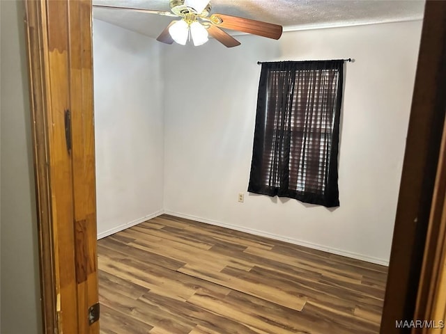 unfurnished room featuring a textured ceiling, baseboards, a ceiling fan, and wood finished floors