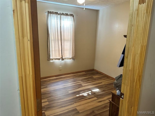 spare room with baseboards, a ceiling fan, a textured ceiling, and wood finished floors