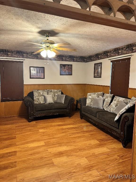 living area with a ceiling fan, wainscoting, and light wood-type flooring