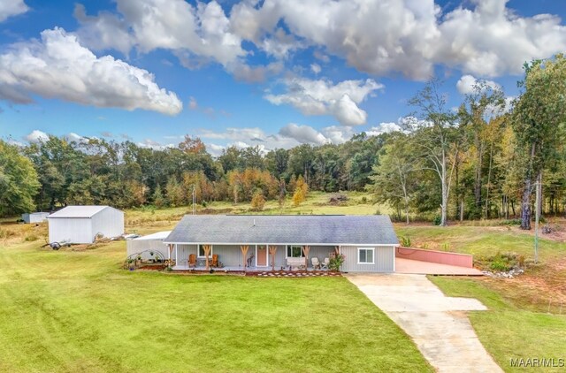 view of front of property with covered porch, a shed, and a front lawn