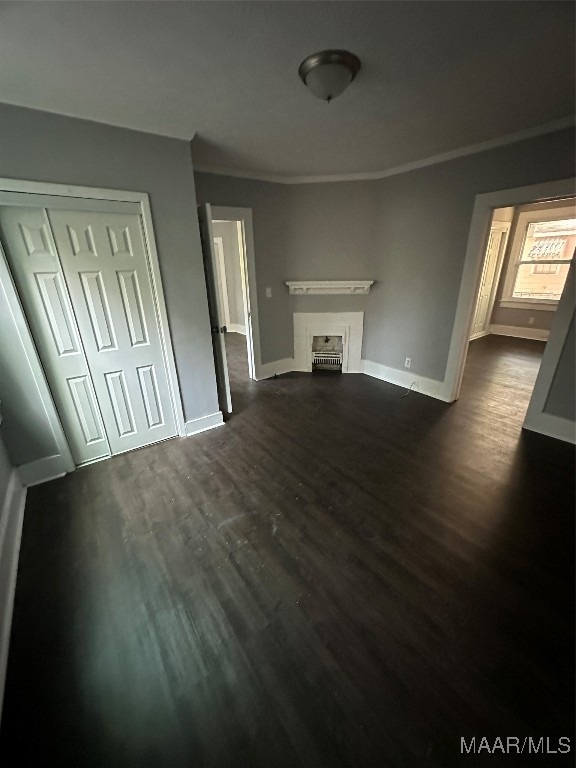 unfurnished living room with crown molding and dark hardwood / wood-style floors