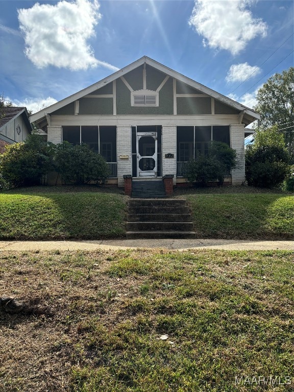 view of front of home featuring a sunroom and a front lawn