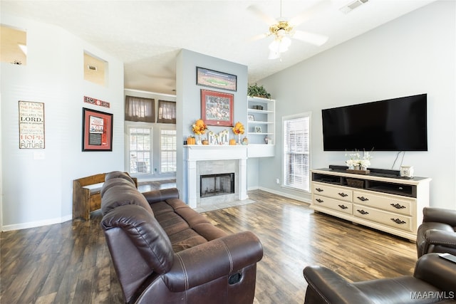 living room featuring a tiled fireplace, dark hardwood / wood-style floors, ceiling fan, and vaulted ceiling