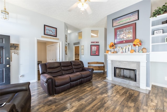 living room with ceiling fan, a textured ceiling, high vaulted ceiling, a fireplace, and dark wood-type flooring