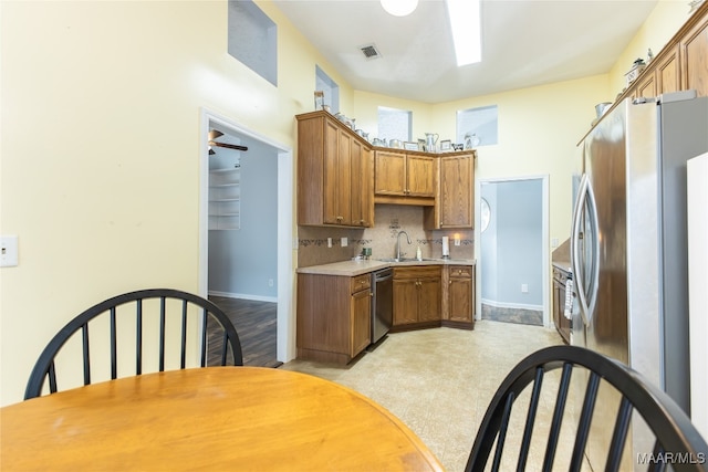 kitchen featuring stainless steel appliances, sink, ceiling fan, a towering ceiling, and decorative backsplash