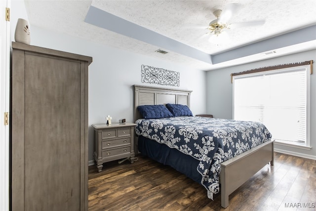 bedroom featuring a textured ceiling, multiple windows, dark hardwood / wood-style floors, and ceiling fan