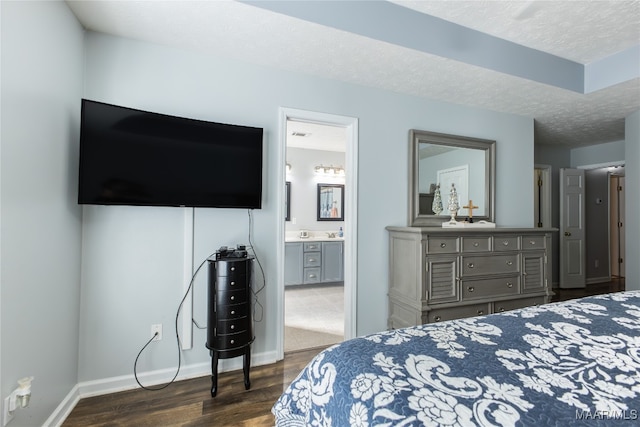 bedroom featuring dark hardwood / wood-style flooring, a textured ceiling, and ensuite bathroom