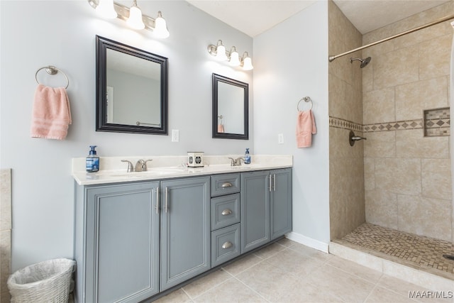 bathroom featuring tile patterned flooring, vanity, and a tile shower