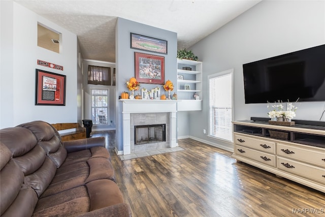 living room featuring lofted ceiling, dark hardwood / wood-style floors, a textured ceiling, and a tiled fireplace