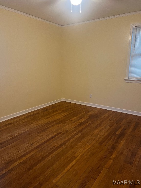 empty room featuring ornamental molding and dark wood-type flooring