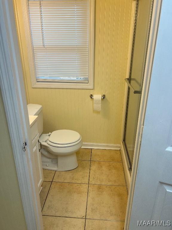 bathroom with toilet, tile patterned flooring, wooden walls, an enclosed shower, and vanity