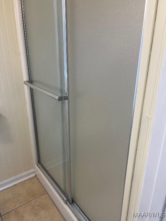 bathroom with an enclosed shower and tile patterned floors