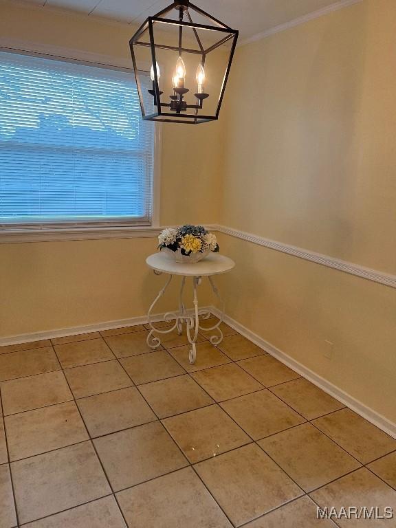 unfurnished dining area featuring an inviting chandelier, ornamental molding, and tile patterned floors