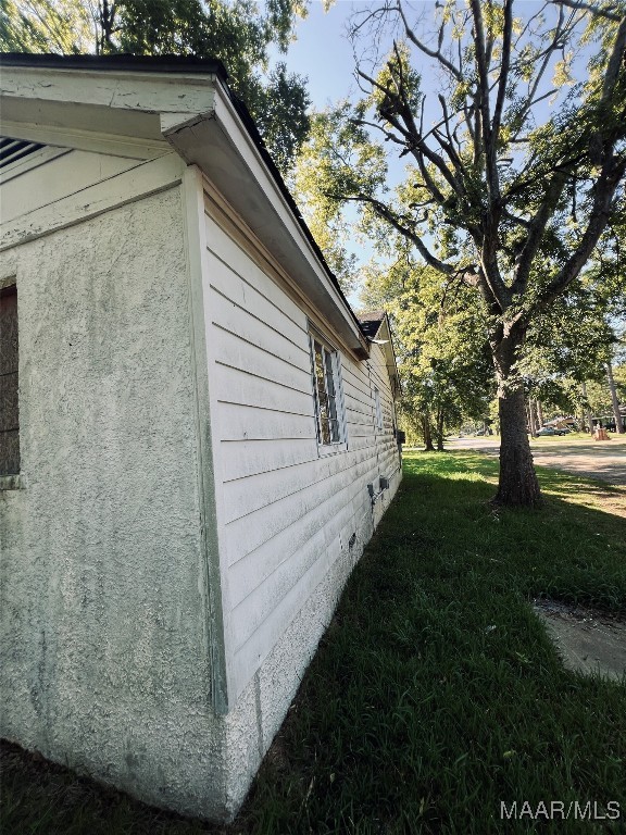 view of side of home with a yard