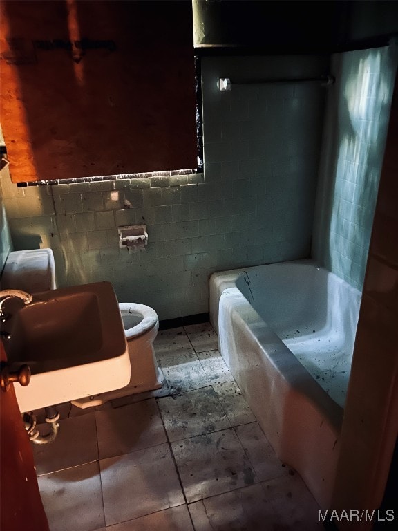 bathroom featuring toilet, sink, tile walls, and a tub