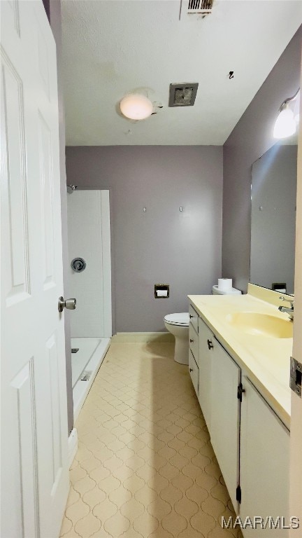 bathroom with walk in shower, vanity, tile patterned floors, and toilet