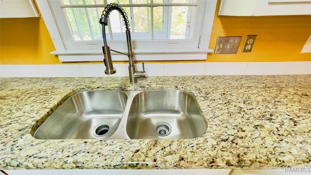 details featuring white cabinetry, sink, and light stone countertops