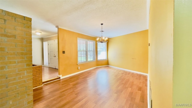 spare room featuring wood-type flooring, a textured ceiling, a chandelier, and ornamental molding