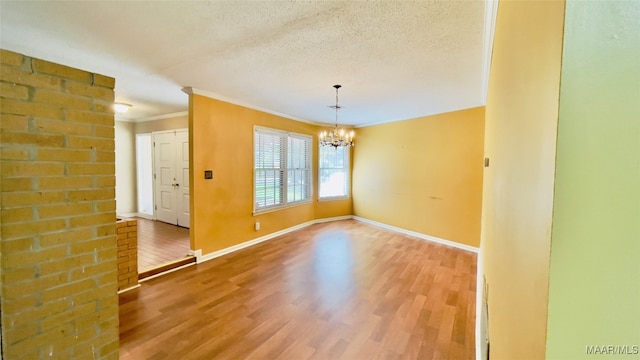 unfurnished room with hardwood / wood-style flooring, a chandelier, a textured ceiling, and crown molding