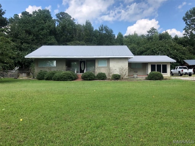 single story home with metal roof, fence, and a front lawn