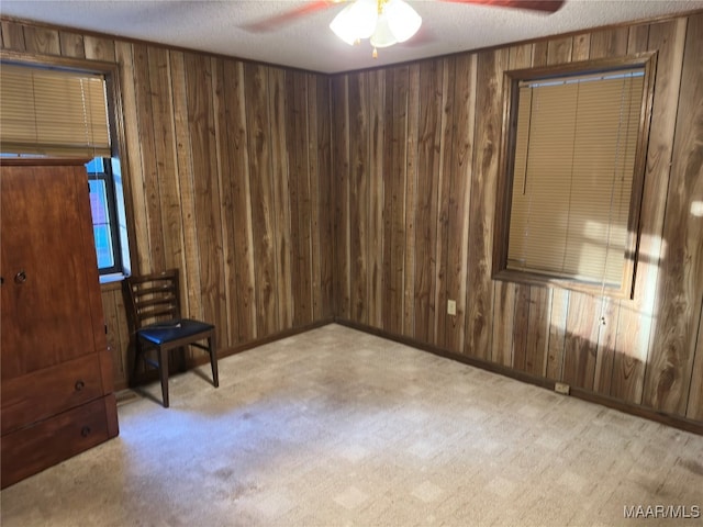 unfurnished room with wood walls, a textured ceiling, light carpet, and ceiling fan