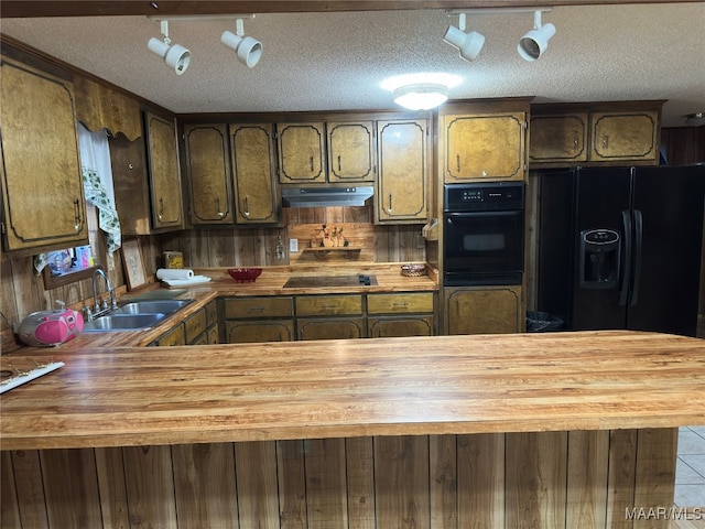 kitchen featuring sink, black appliances, a textured ceiling, light tile patterned floors, and wood counters