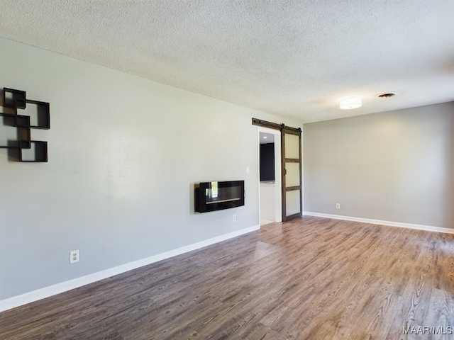 empty room featuring hardwood / wood-style floors, a barn door, and a textured ceiling