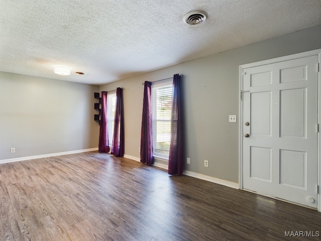 interior space with a textured ceiling and dark hardwood / wood-style floors