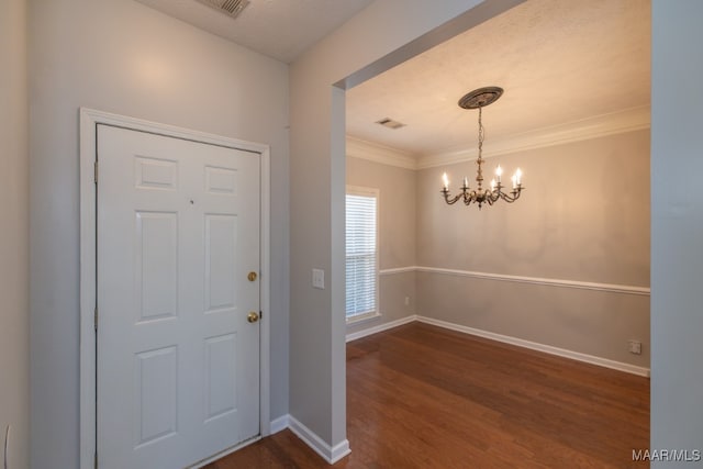 entryway with a textured ceiling, a notable chandelier, dark hardwood / wood-style floors, and crown molding