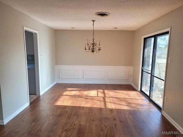 unfurnished dining area featuring an inviting chandelier, hardwood / wood-style flooring, and a textured ceiling