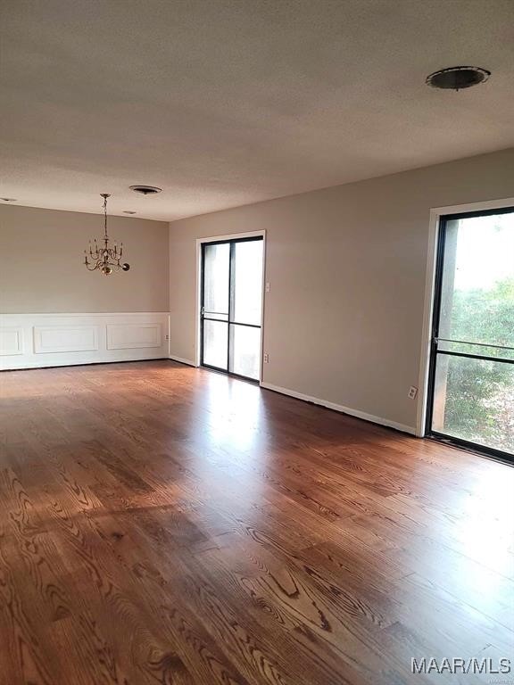 empty room featuring a chandelier, hardwood / wood-style floors, and a healthy amount of sunlight