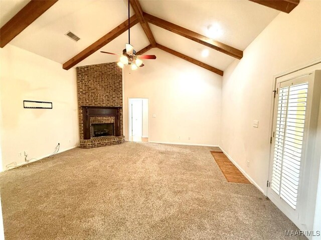 unfurnished living room with high vaulted ceiling, a brick fireplace, beam ceiling, and carpet flooring